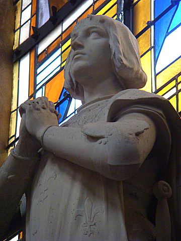 Picture of a statue of Joan of Arc with hands clasped inside a church in Blois